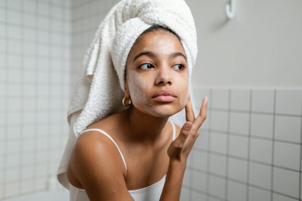 Young woman enjoying a refreshing skincare routine with face cream in a modern bathroom.