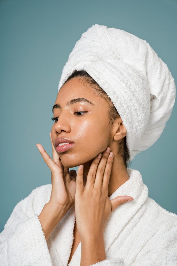 Young woman in a spa setting applying skincare with a fresh clean look.